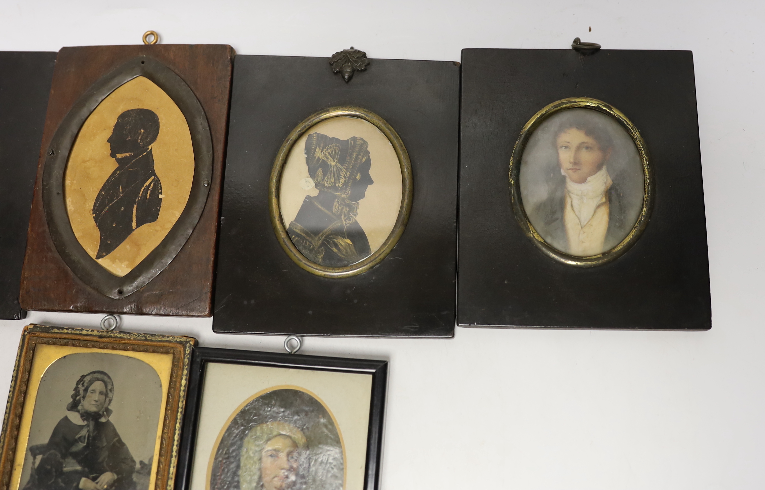 A quantity of miniatures comprising oil of an 18th century gentleman wearing a wig, three 19th century silhouettes, Victorian blue and white photograph and one other
